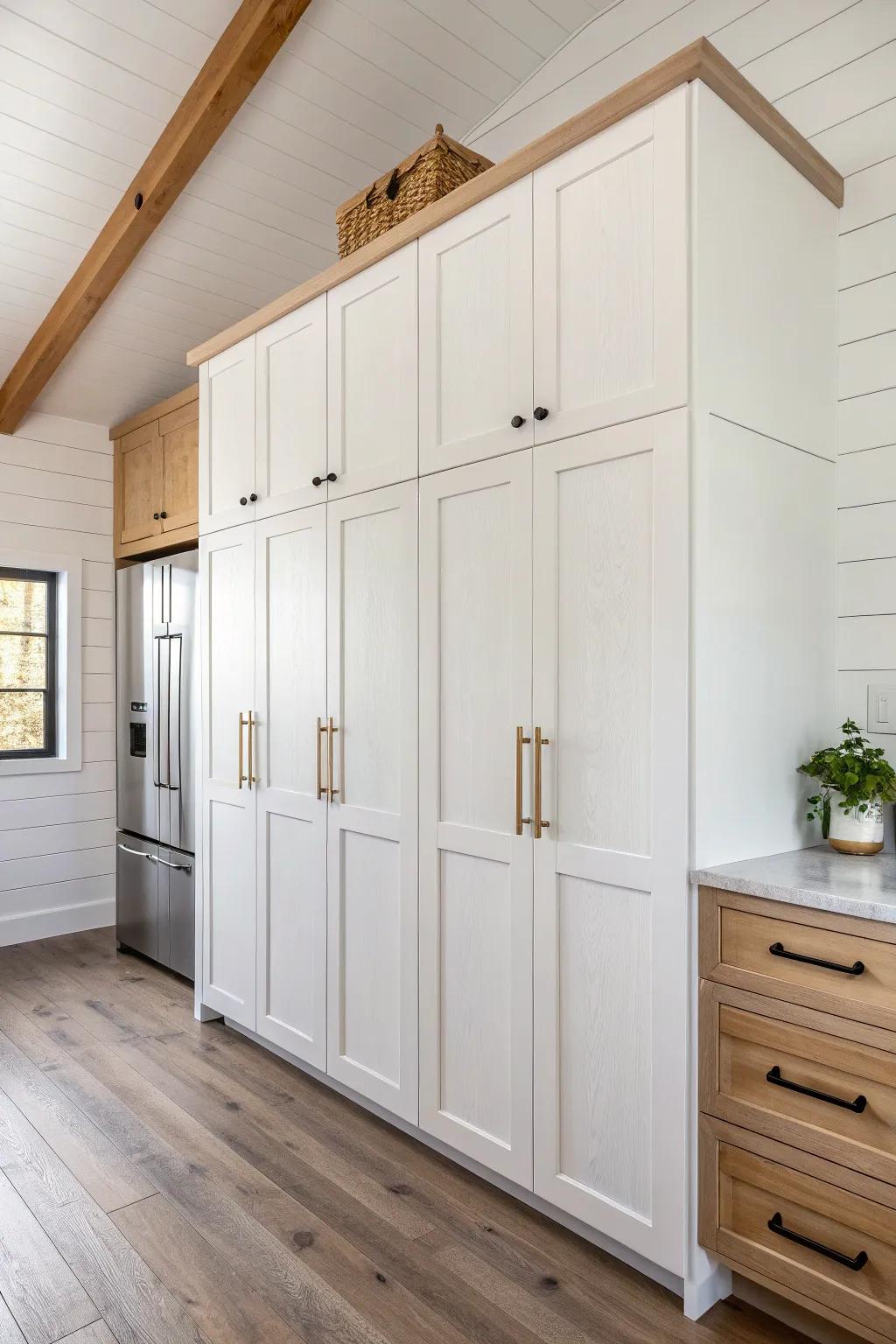 Wall-to-wall pantry run: tall plywood-built cabinets that hide broom + utilities in style.