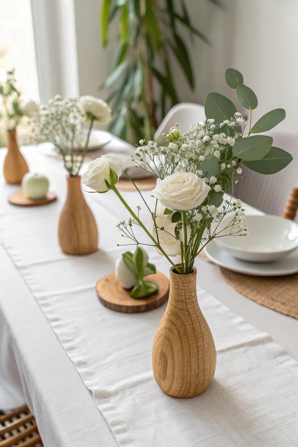 Mini oak bud vases in a simple line keep a white dining table light, modern, and charming.