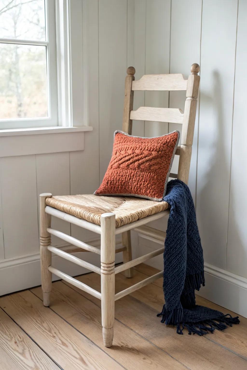 Farmhouse ladder-back corner chair with lightly distressed paint, cozy pillow, and chunky throw.