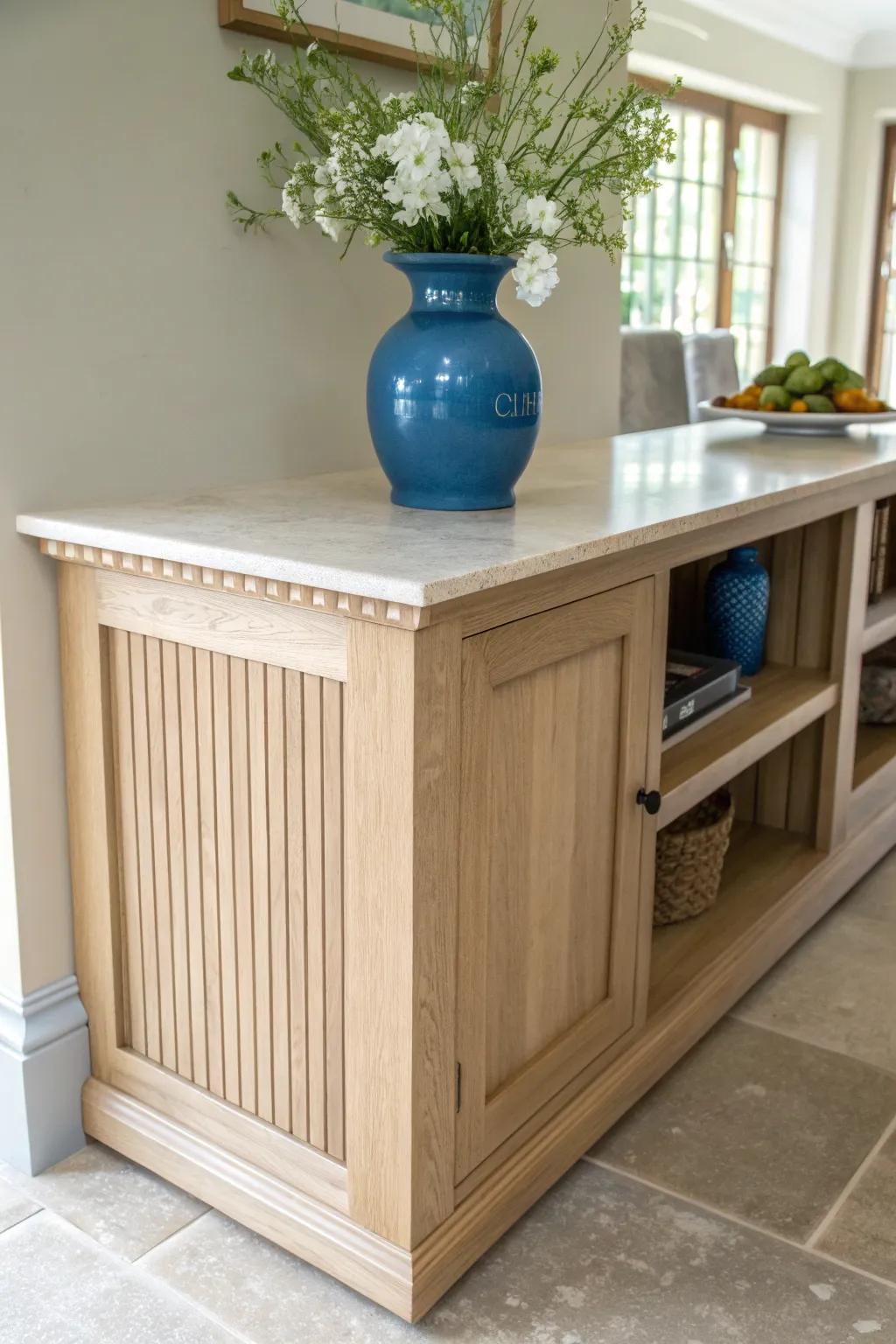 A French-country flower nook beside the sink—oak, stone, and a bold blue vase pop.