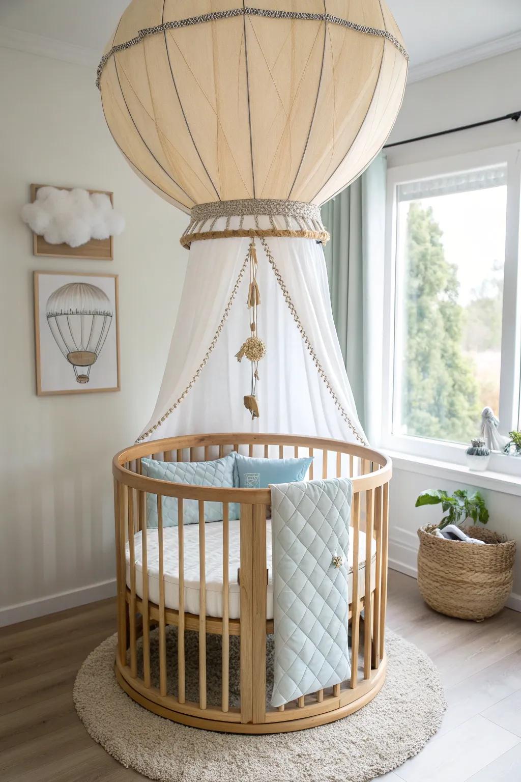 Round oak crib under a hot-air-balloon canopy—pale blues, warm whites, and dreamy clouds.