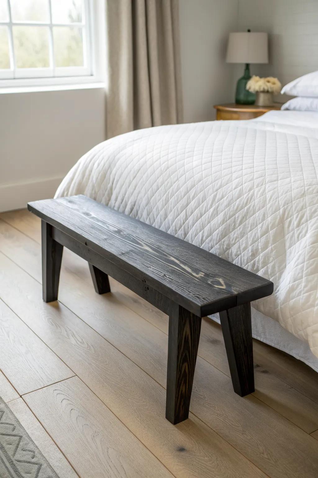A charred-wood bench adds bold contrast and artisan texture to a light, airy bedroom.