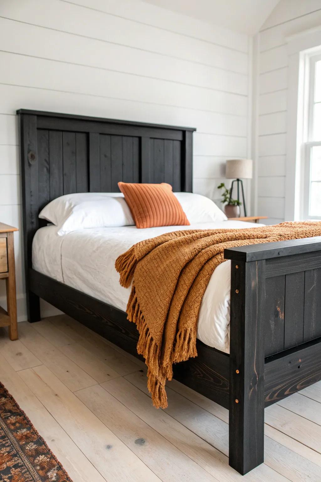 Black bed frame, crisp white linens, and a caramel throw—minimal, boho, boutique contrast.