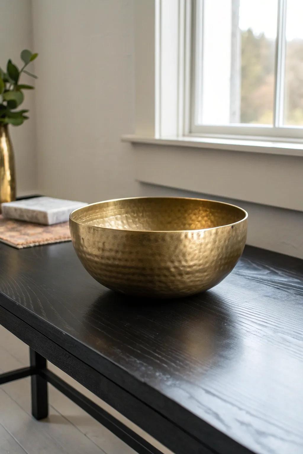 A warm brass bowl catches the light on a black coffee table—instant contrast and elegance.