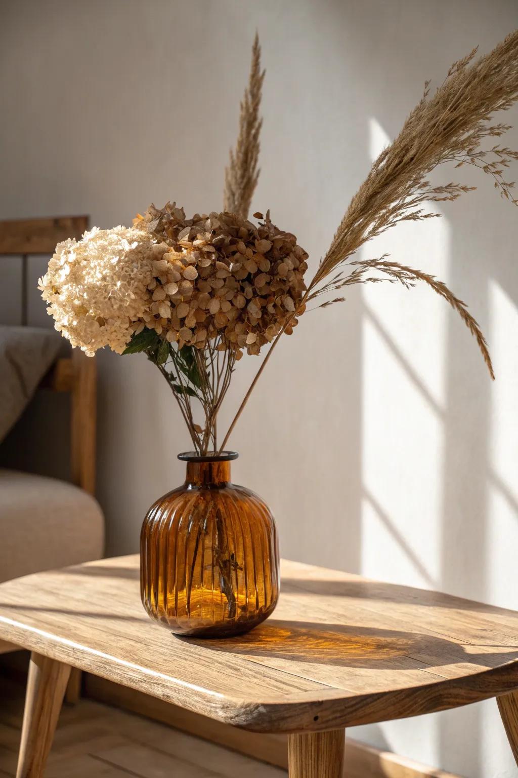 Amber glass vase with dried hydrangeas adds moody fall warmth to a simple oak coffee table.